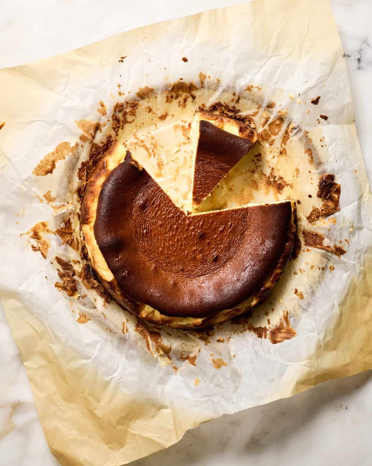 Basque cheese cake sliced on a piece of parchment.