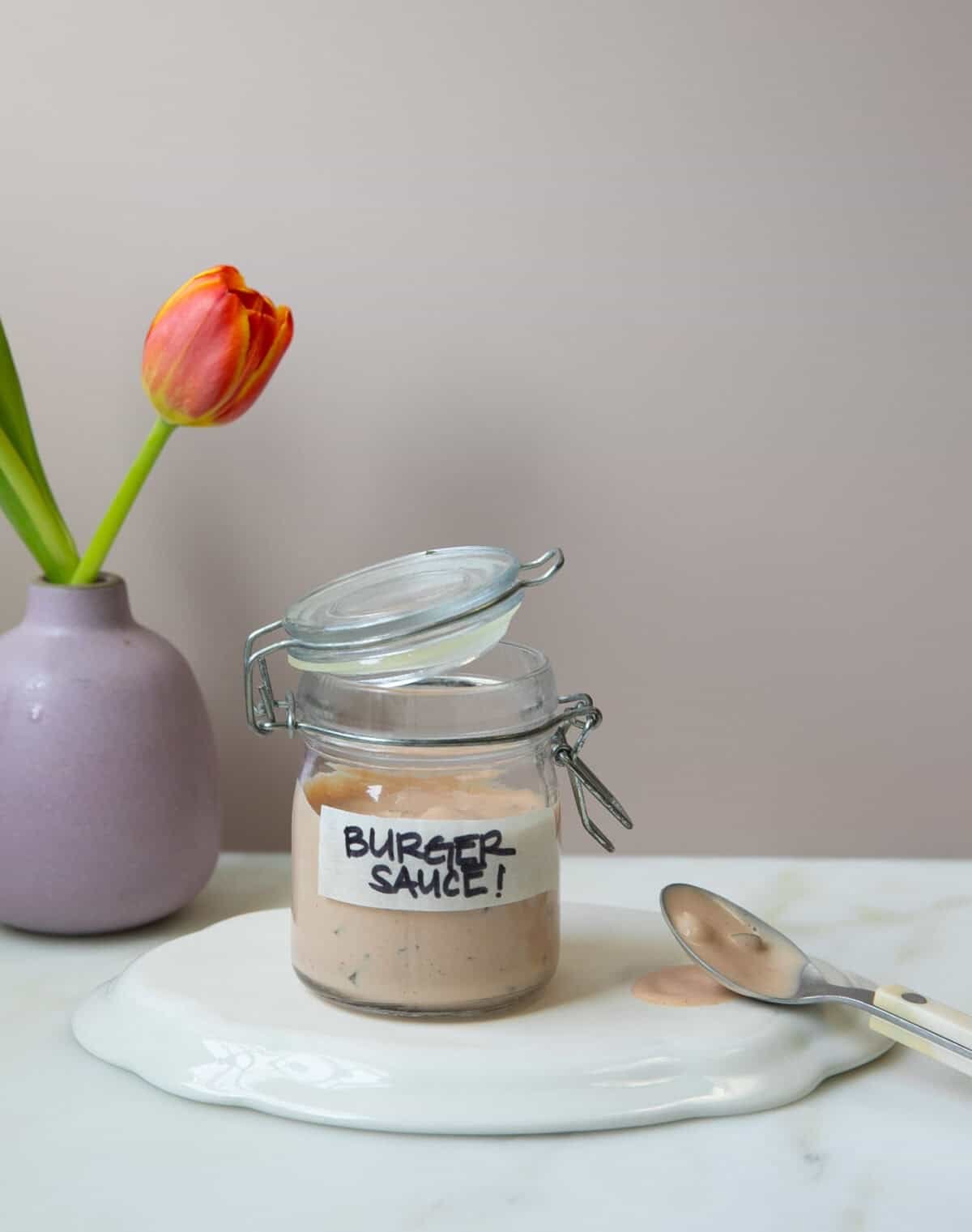 Burger sauce in a jar with a few flowers on the side.