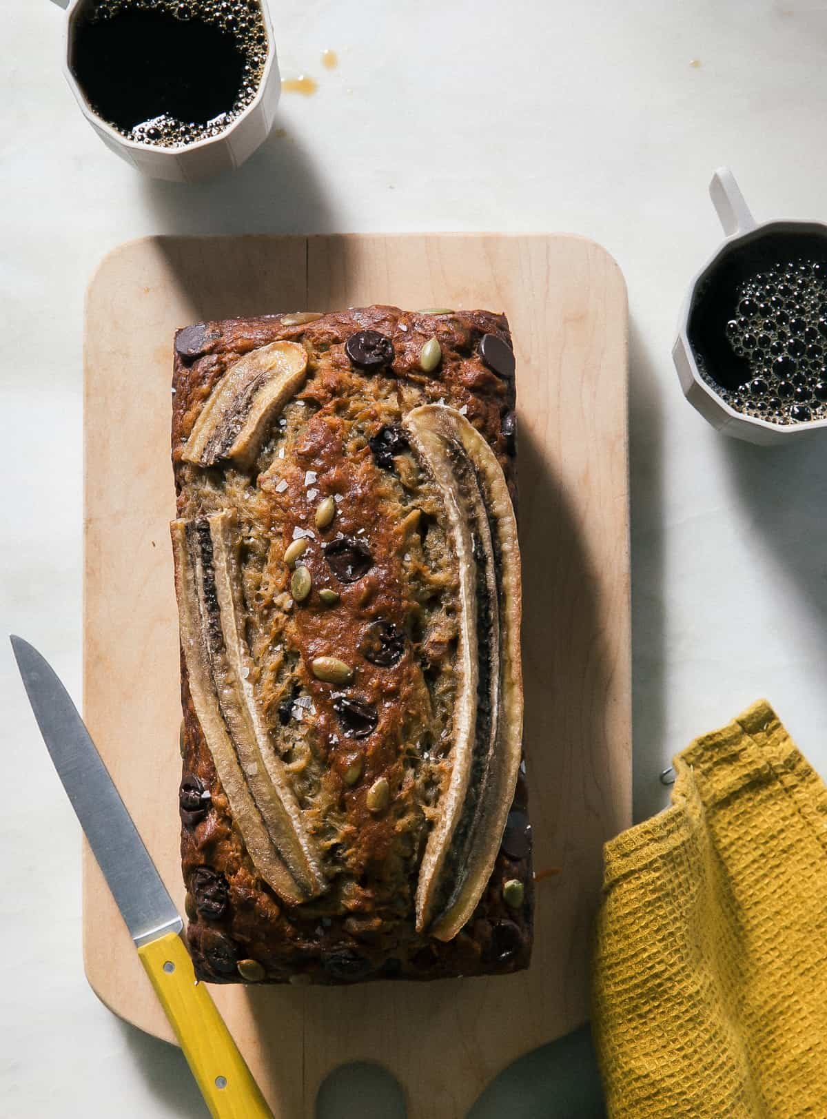 Easy Banana Nut Bread on cutting board with coffees.