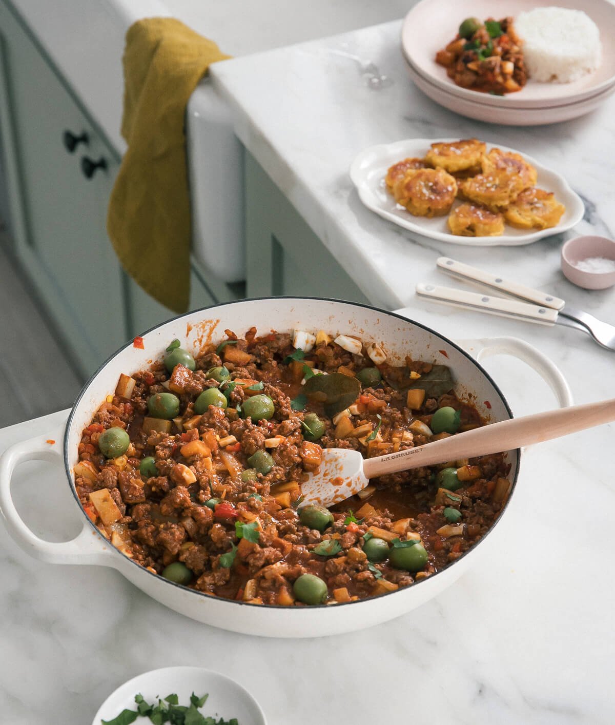 Picadillo in pot with Tostones in the background.