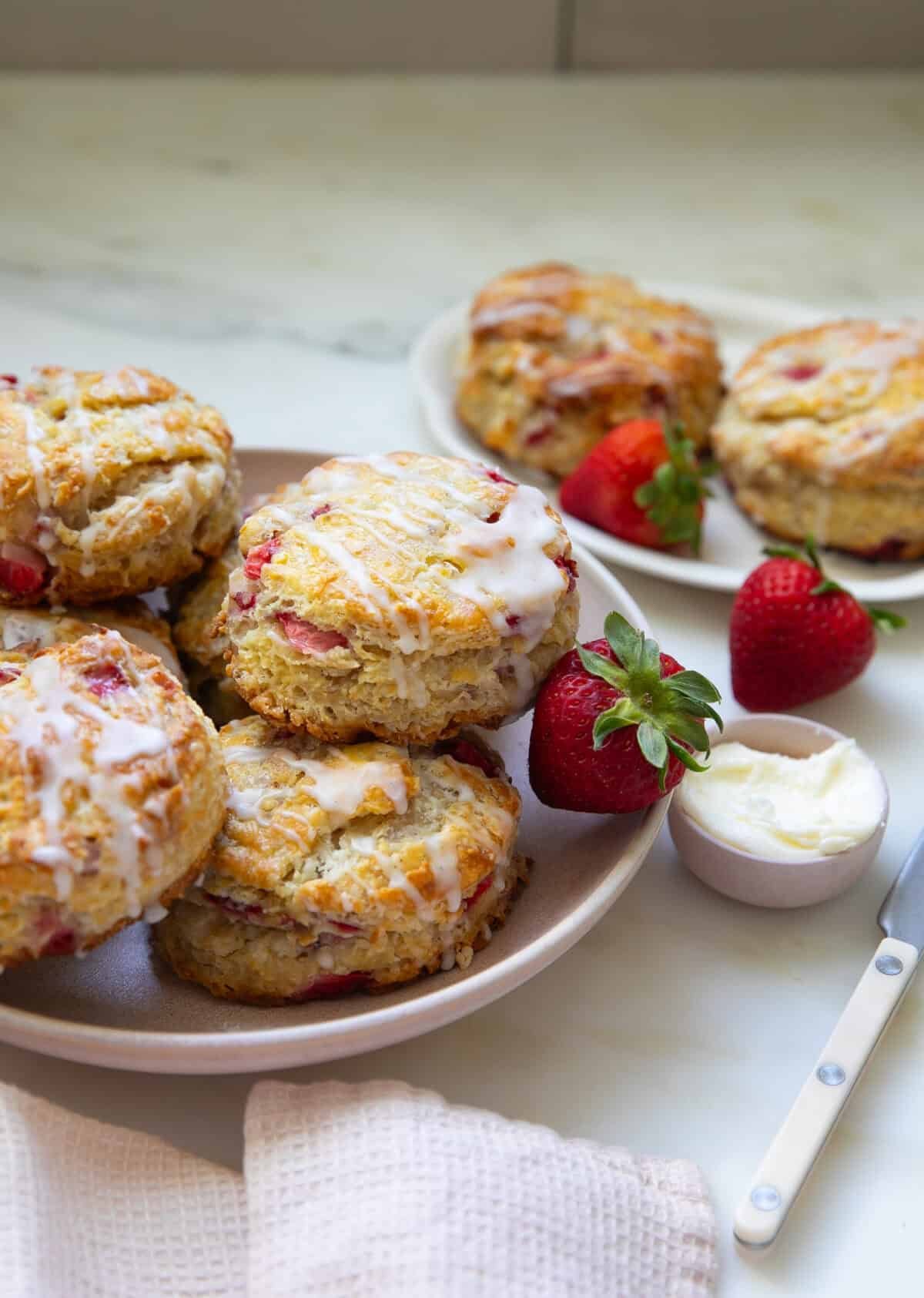 Strawberry biscuits with strawberries on the side with butter on a plate.