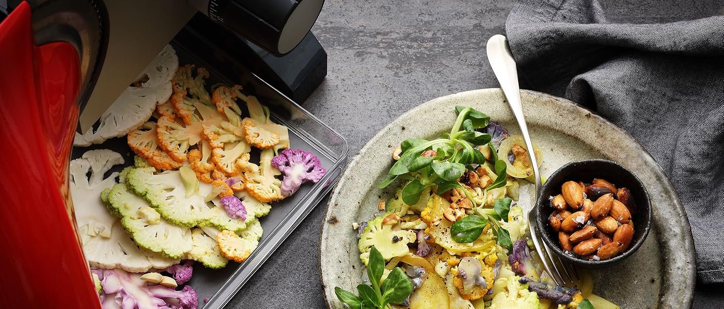 Two plates of colorful salads with mixed greens, vegetables, and nuts. One plate features a side of roasted nuts in a small bowl.